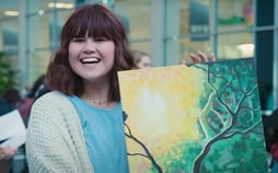 BYU student, Ashley Savage, smiling and holding a piece of artwork