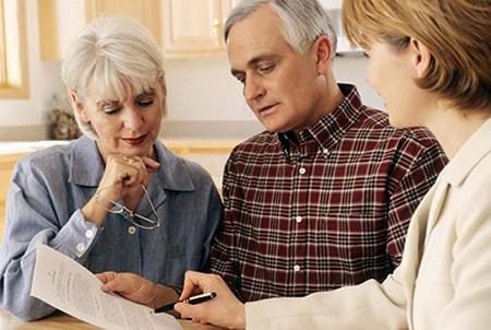 Husband and wife looking at a printed document with their financial advisor